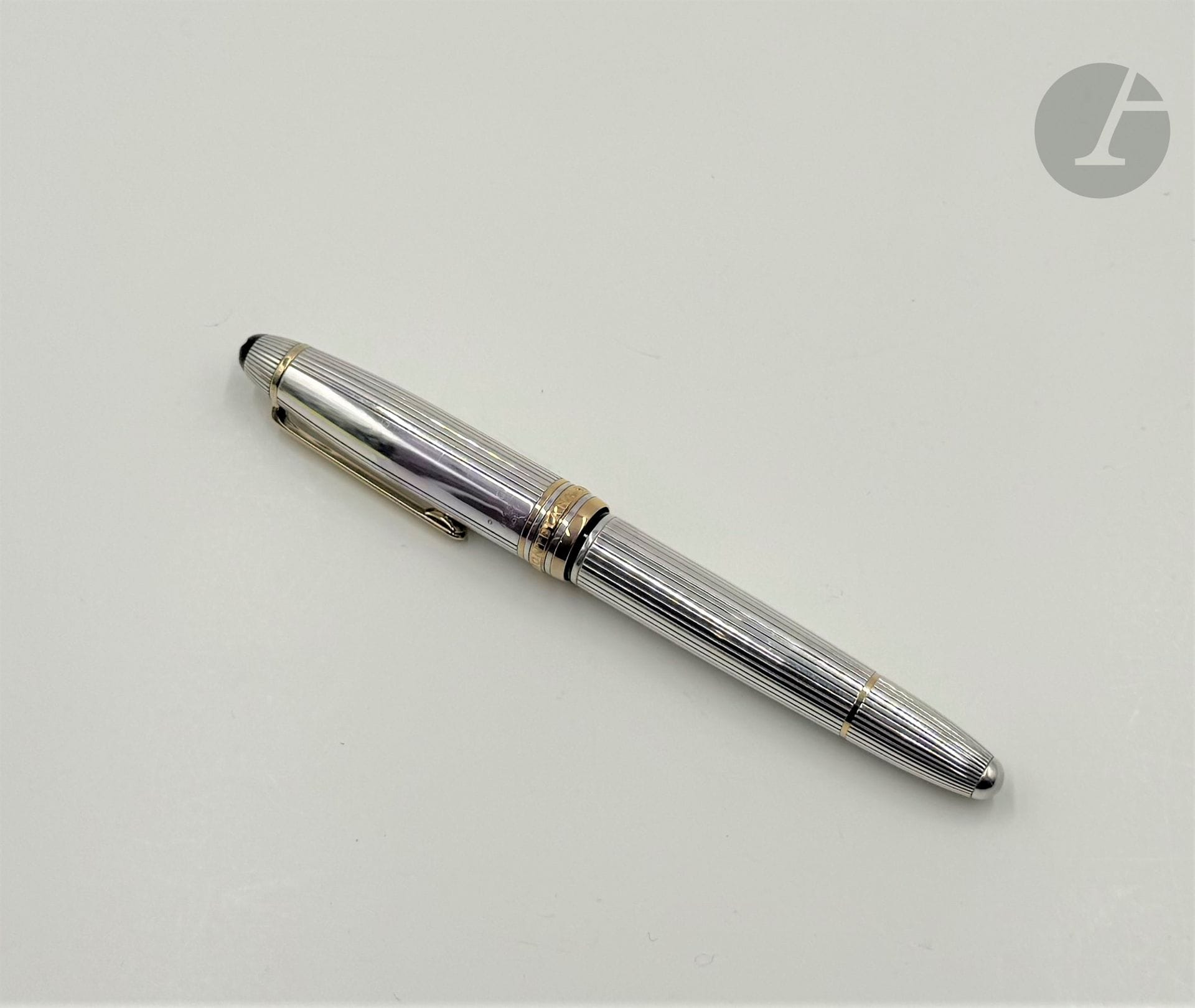MONTBLANC. St
Meisterstück
Silver fountain pen, 18K (750) two-tone gold nib, guilloche-cut body, gold-plated metal appointments, black and white lacquered cap. 
Numbered ILG200347
Length: 14.5 cm
