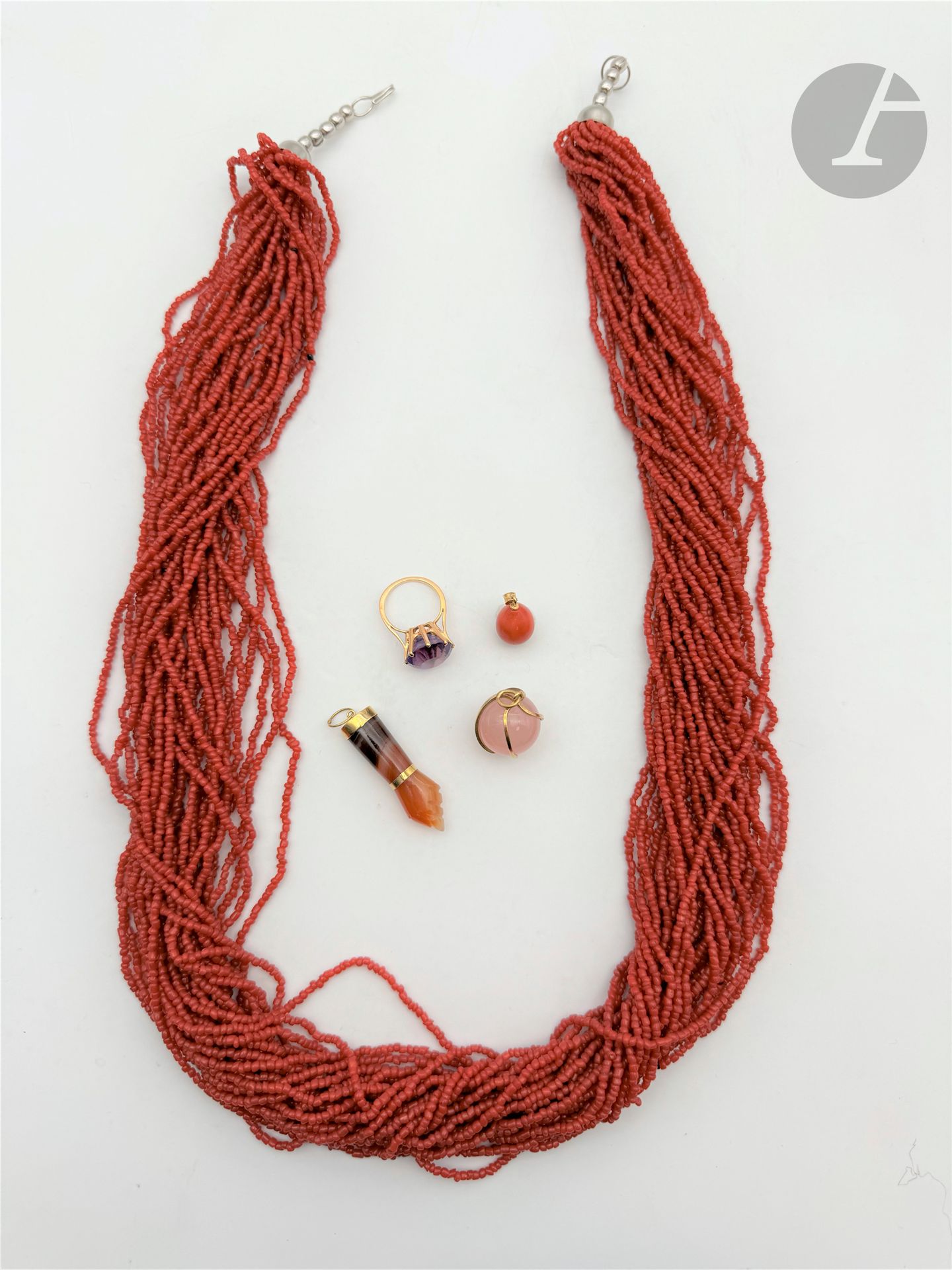 Suite de bijoux en or 14K (585) et 18K (750), les trois premiers en or 18K comprenant : une bague sertie d'une améthyste de ronde ; un pendentif œuf en corail  et un pendentif figa en agate sculpté ; le quatrième, un pendentif boule de quartz rose enserré dans une monture en or 14K (585). Poids brut or 18K : 15,1 g. Poids brut or 14K : 9,9 g (on joint un collier multi-rangs fantaisie)
