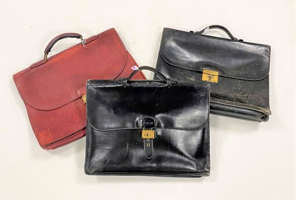 HERMÈS Paris Made in France
Sac à dépêches en box noir, chiffré P.C.R, fermoir en métal doré, avec ses deux clés, 40 x 30 cm (importantes usures, accidents et restaurations). 
On y joint deux cartables (usures, en l'état), l'un Schilz en cuir noir l'autre en cuir rouge griffé Renard