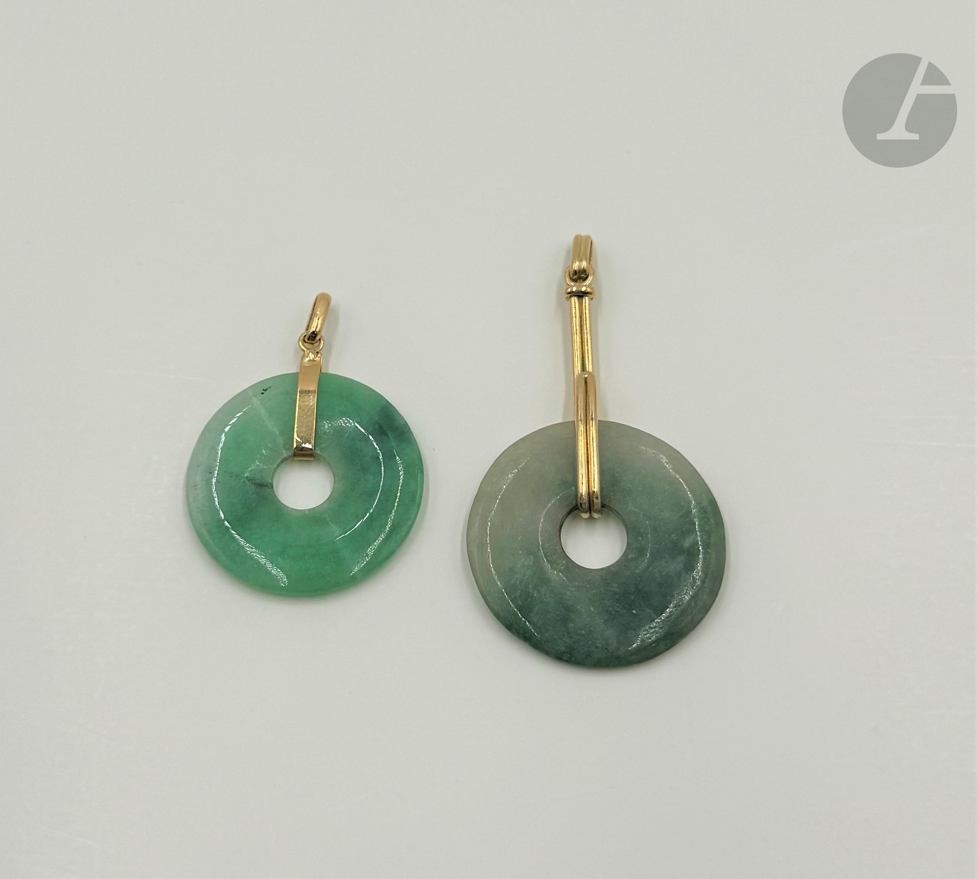 Suite de deux pendentifs "bi" en jade montés en or 18K (750). Diamètre : 3 et 3,2 cm environ. Poids brut : 17,1 g (fêles)