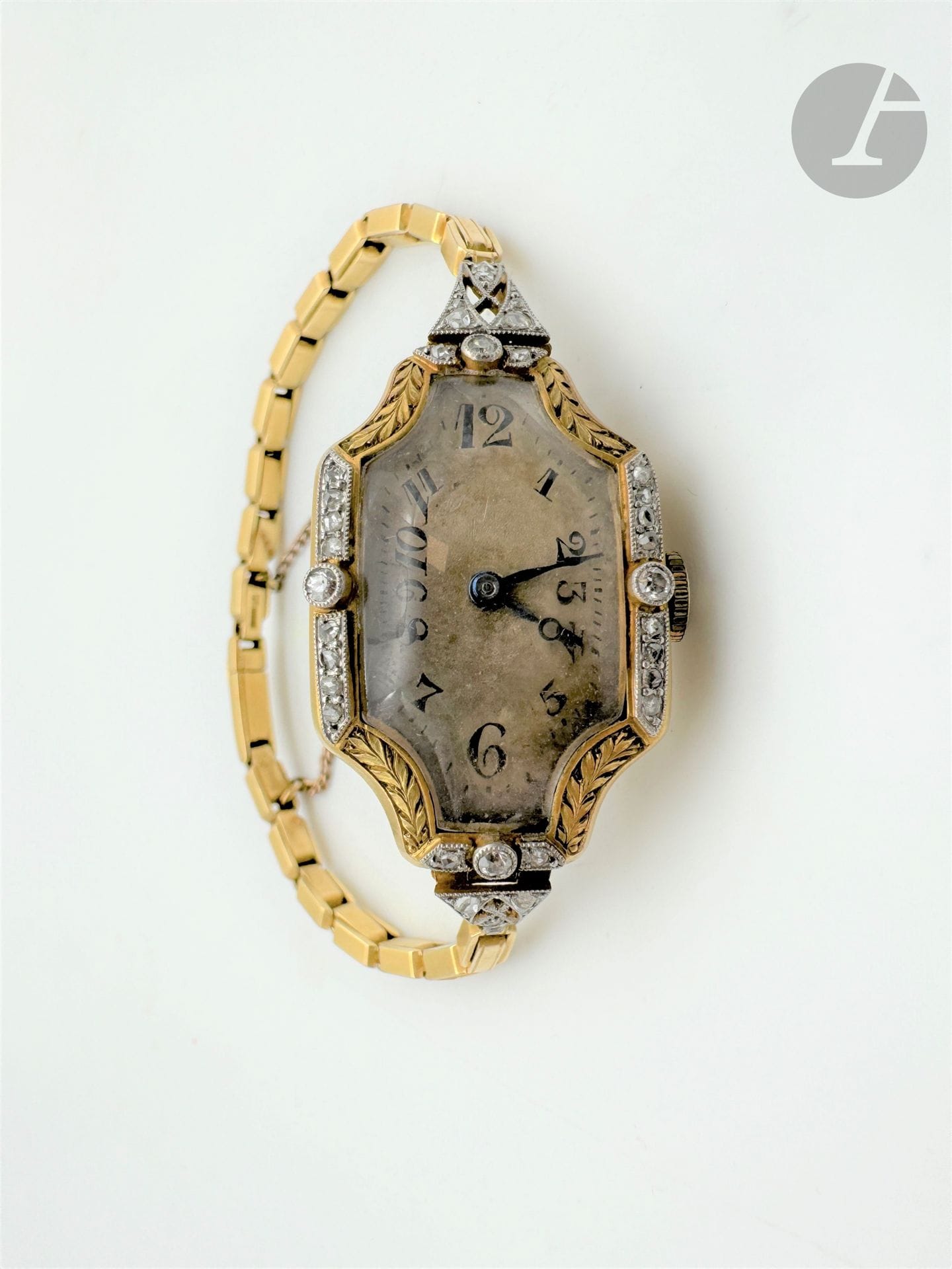 # Montre de dame en or 18K (750) et platine, le bracelet en or articulé de maillons rectangulaires imbriqués, le boîtier quadrangulaire bombé ciselé de feuillages agrémentés de diamants taillés en roses ou taille ancienne, mouvement mécanique. Travail des années 1920. Dimensions boîtier : 2,8 x 2 cm environ. Longueur : 15 cm environ. Poids brut : 22,9 g (fonctionnement non garanti, oxydations)