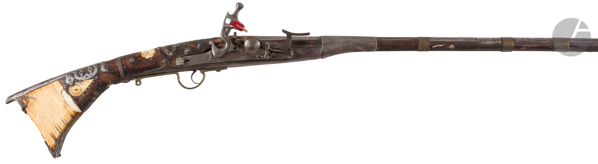 Long fusil à silex d’Afrique du Nord dit Moukalah. 
Canon rond tulipé à la bouche, à pans au tonnerre, maintenu par neuf bagues en fer et laiton. Platine à corps plat. Chien à corps rond. Pontet en laiton. Crosse garnie d’incrustations d’os. Plaque de couche et garnitures en fer.
Longueur: 159 cm
A.B.E. Vers 1830-1850.