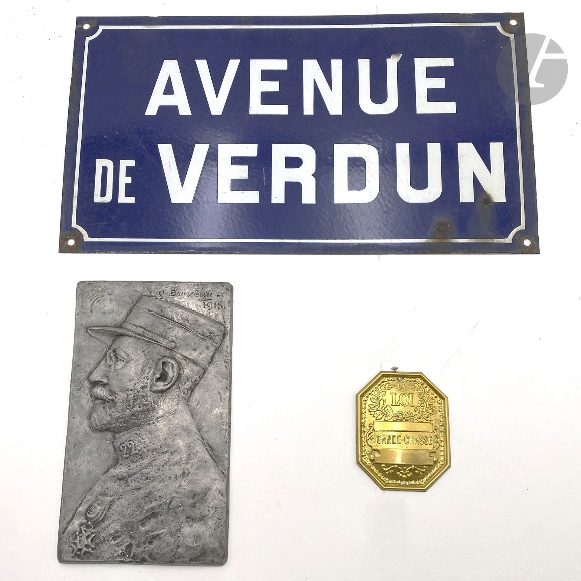 Trois souvenirs : 
- plaque signalétique «AVENUE DE VERDUN». 25 x 45 cm 
- plaque signée «J. BOURDEAU» représentant un officier du 22e régiment. En métal argent. 25 x 15 cm 
- refrappe de plaque de garde-chasse.