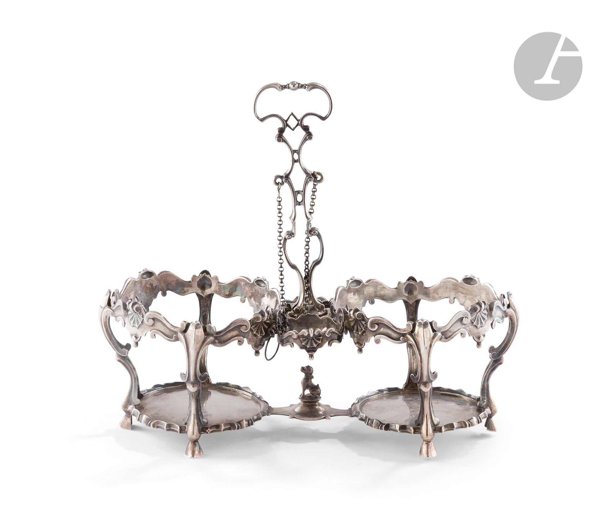 VILLE DE MONS 1767 - BELGIUM
Silver oil and vinegar cruet stand on four sabot feet, the rocaille mounting embellished with shells and scrolls. The openwork, curved and counter-curved central socket is terminated by a central socket. The base features a dog in the round on a small console.
Master goldsmith: an unidentified heart.
Weight : 447 g - length : 22.5 cm - height : 20.5 cm
Condition : the end of one of the two chains is missing.