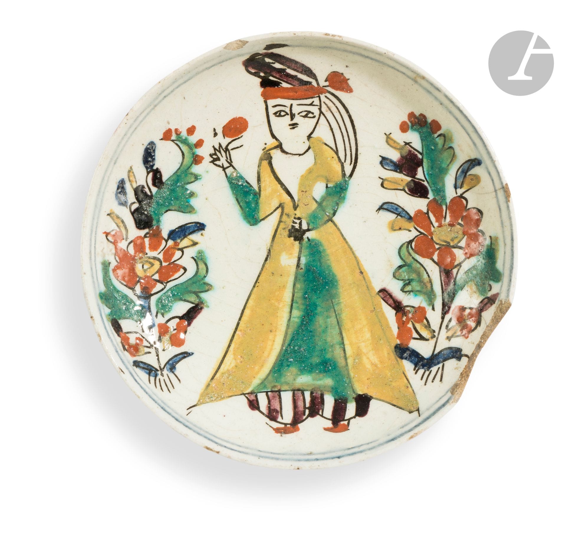 Coupelle à la jeune femme, Turquie ottomane, Kütahya, seconde moitié du XVIIIe siècle
Petite coupe sur pied cylindrique en céramique siliceuse peinte aux engobes colorés sur fond blanc sous glaçure transparente. Une jeune femme, portant un caftan jaune et une robe verte par-dessus un salwar à rayures aubergine, et un turban assorti à ce dernier, tient une fleur dans sa main droite. Des gerbes florales l’encadrent et deux lignes bleues au bord encerclent le tout. 
Hauteur : 3,6 cm ; diamètre : 14,2 cm 
Trou de suspension, égrenures, manque sur un bord.

A Kutahya Pottery Dish, Ottoman Turkey, second half of the 18th century