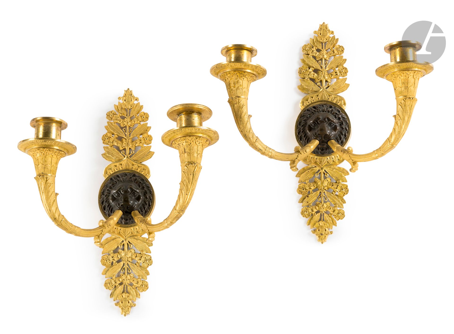 Paire de bras de lumière aux mufles de lion en bronze patiné et bronze doré, à deux branches et décor de feuilles de laurier, feuillages et fleurs
Epoque Empire.
H : 25 cm, L : 20 cm