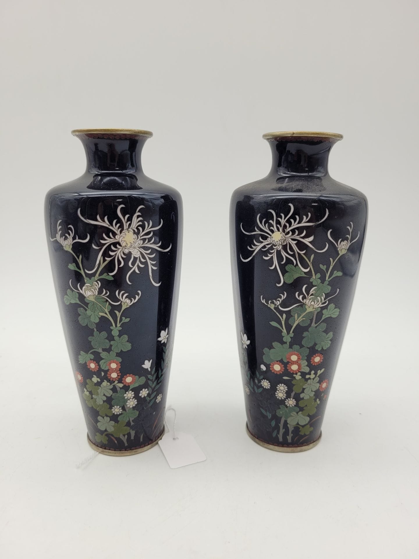 Paire de vases en émail cloisonné sur cuivre, Japon, époque Meiji (1868-1912)
De forme conique tronquée inversée à col évasé au niveau de l'épaulement, chacun à décor de chrysanthèmes et autres fleurs polychromes sur un fond bleu nuit.
Hauteur : 15 cm
Petits éclats.