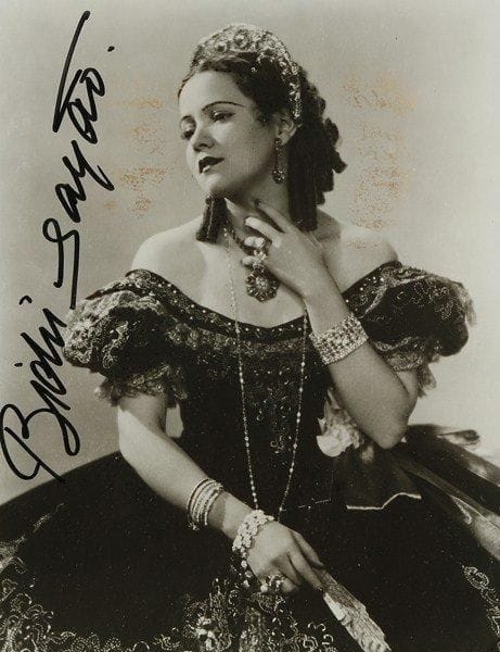Baldwina de Oliviera, dite Bidu SAYAO (1902-1999) soprano brésilienne. Photographie signée; 23,5 x 18 cm (encadrée, lég. mouill.).Beau portrait dans le rôle de Violetta (La Traviata)