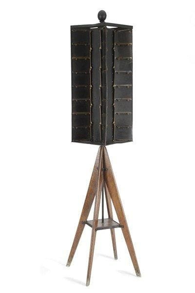 KIOSQUE À CARTES POSTALES en tôle et piètement en bois naturel. Hauteur: 180 cm (Petits manques).Le présentoir tournant en tôle laqué noir à quatre compartiments comporte 96 supports de cartes. Le piètement quadripode, réuni par une tablette bordée de métal, soutient le système rotatif