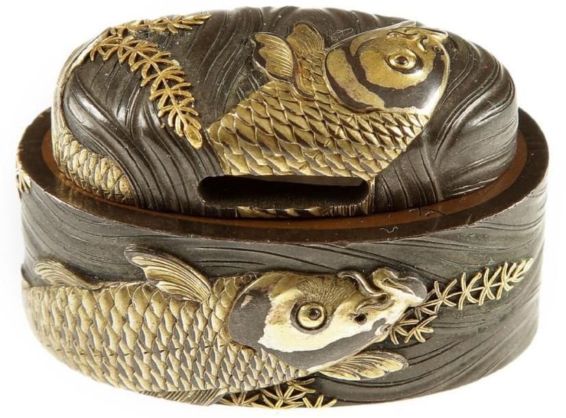 JAPON
Fushi et kashira en shibuichi décorés en relief et incrusté de cuivre jaune de carpes nageant parmi les algues sur fond de vagues avec le reflet de la lune. Signé Sekkoku Masatsune