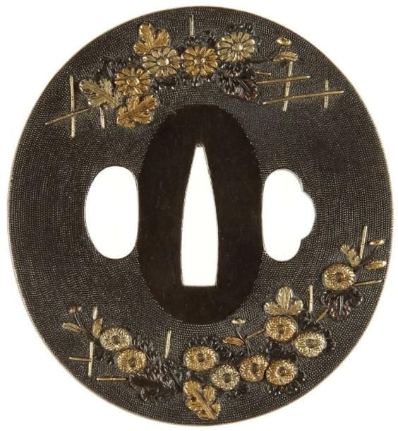 JAPON
Nagamaru gata en shibuichi à fond de nanako, à décor incrusté de shakudo et cuivre jaune de chrysanthèmes dans leur feuillage.H. 7,8 cm