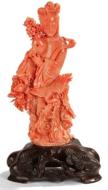 CHINE - XXe siècle
Statuette de jeune femme debout en corail rouge portant un vase à côté d'un phénix.H. 15 cm