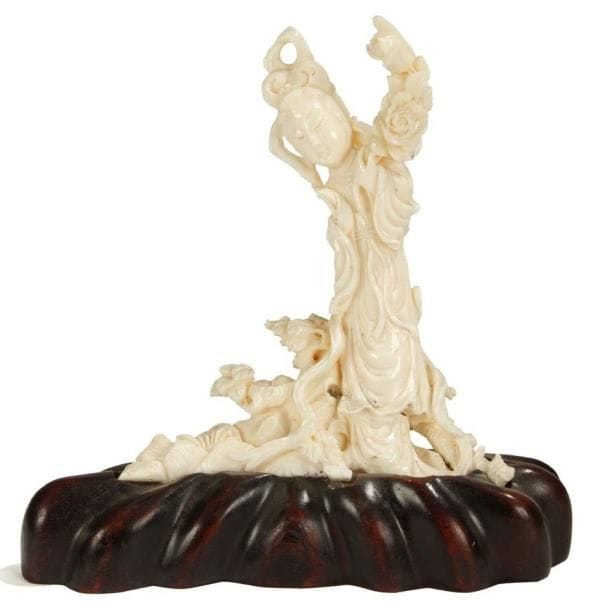 CHINE - XXe siècle
Groupe en corail blanc, jeune femme debout sur un tronc d'arbre tenant une branche de pivoines. Socle en bois.H.: 15 cm
