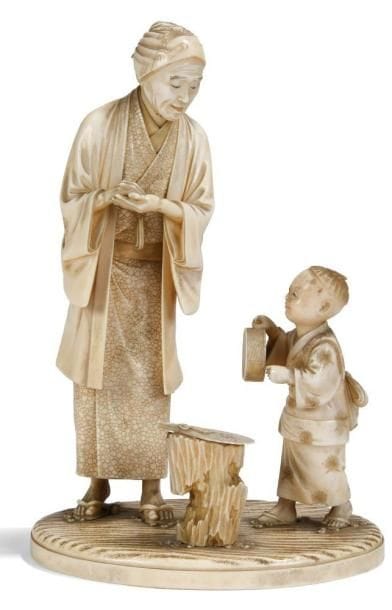JAPON
Okimono en ivoire à patine jaune représentant une femme et un enfant debout devant un éventail posé sur une souche. Signé dans un cartouche en laque rouge Nobumasa. H.: 18 cm