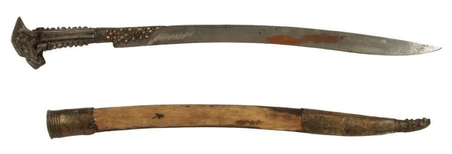 Armes diverses MALAYSIE - XXe.Klewang, la lame légèrement courbée et pointée, le fourreau en métal argenté et incrusté de cabochons et décorée de fleurs en filigrane. (Restaurations et petits manques).L. tranche: 52,2 cm