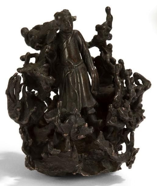CHINE - Epoque MING (1368 - 1644), XVIIe siècle
Groupe en bronze à patine brune représentant un lettré debout parmi un rocher et tenant un miroir. (Accidents). H.: 11 cm