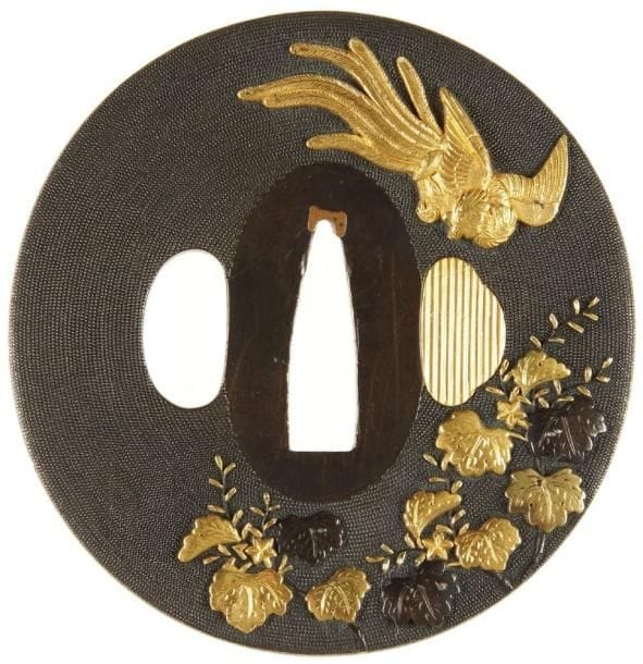 JAPON
Nagamaru gataen shibuichi nanako ji à décor incrusté de cuivre jaune et shakudo d'un phénix volant au-dessus de fleurs et feuillage. Signée Ichiguro Masatsune.H. 7,2 cm