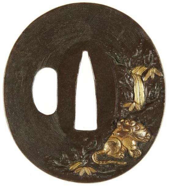 JAPON
Nagamaru gata en shibuichi nanako ji à décor ciselé et incrusté de cuivre jaune d'un tigre assis au bord d'une cascade. Non signée.H. 6,1 cm