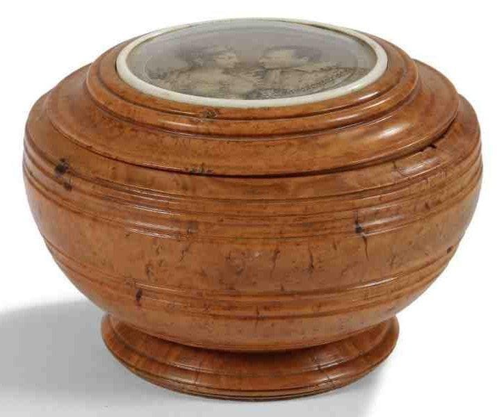 Boîte ronde, en loupe de thuya, mouluré. Le dessus orné d?une gravure sous verre, cerclée d?un jonc d?ivoire, représentant Marie Louise d?Autriche et Napoléon 1er Empereur. XIXe siècle. Fente. Haut.: 11 cm - Diam.: 16 cm