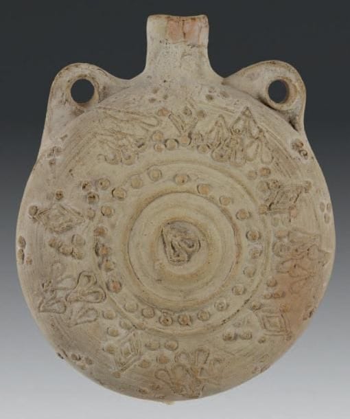 Flasque, Mésopotamie, XIIe-XIIIe siècle Poterie à panse circulaire à deux petites anses annulaires et haut col, à décor moulé et appliqué de perles, losanges et motifs cordiformes. H.: 13 cm