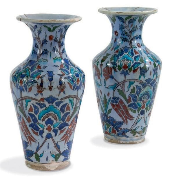 Deux vases balustres de style Iznik, France, début du XXe siècle Céramique à décor polychrome de rinceaux floraux sous glaçure bleutée. A la base, étiquette "Collection Rousselot. Exposition à Lyon juillet 1914". H.: 29 cm (Fractures recollées au rebord)