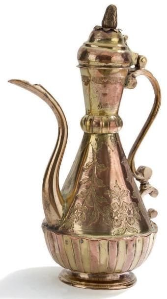 Aiguière, porte-savon et bassin ottoman, en cuivre, Turquie, XIXe siècle. Aiguière à panse piriforme, anse en volute en accolade, bec verseur incurvé sur petite base. Col évasé et annelé surmonté d'un couvercle en dôme à prise en pomme de pin. Cuivre avec traces de dorure, tombak, gravé de guirlandes fleuries sur la panse et de godrons en parties basses; porte-savon à décor ajouré et repoussé de médaillons en amande. Le bassin reprend sur le rebord le même décor de l'aiguière. H. totale: 43 cm - D. du bassin: 29 cm Pour un modèle similaire, voir I. Gûndag Kayaoglu, Tombak, Istanbul, 1992, p.27