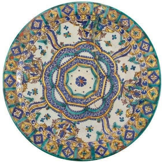 Plat, mokhfia, Maroc, Fès, signé et daté 1332 H./1913 Grand plat en faïence, à décor polychrome et rehauts de minium d'un large octogone inscrit dans un polylobe bordé de compositions florales et de motifs en esse. Frise de quadrilobes au rebord. D.: 50,5 cm (Fracture et réparations par cordage recouvertes de minium) Provenance: collection J.M.G., Paris
