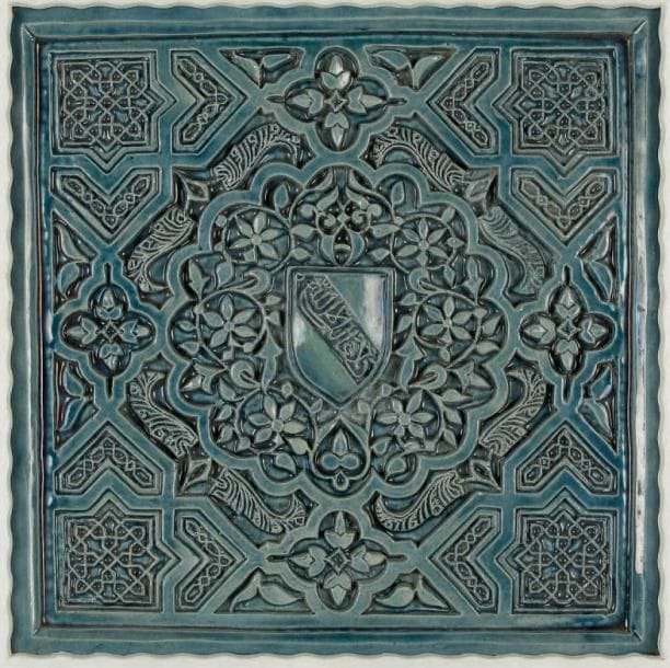 Grand carreau en céramique bleu-gris au blason nasride, France, fin XIXe siècle Décor moulé reprenant le style des stucs du palais de l'Alhambra de Grenade. Composition tapissante de motifs géométriques imbriqués autour d?une rosace portant dans un écusson la devise nasride en bande «Il n'y a pas de vainqueur hormis Dieu». Dim: 37 x 37 cm