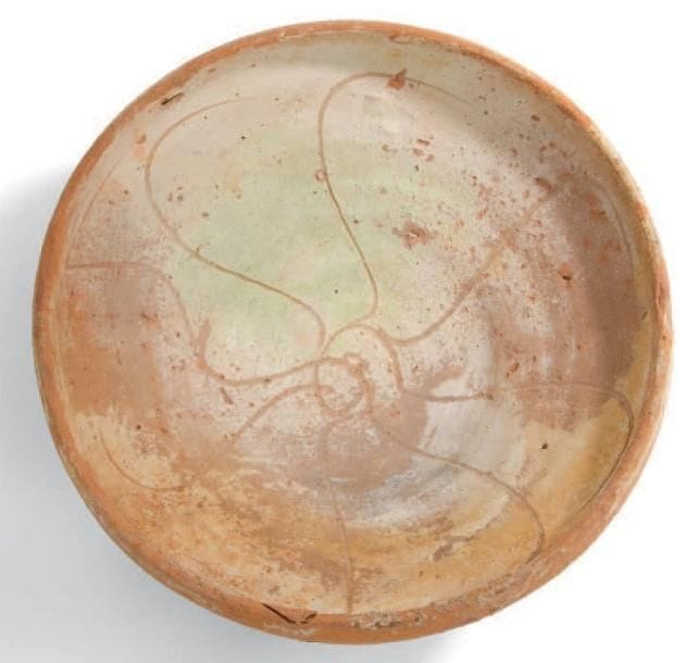 Grande coupe à l'ophiure, Empire byzantin, fin XIIe-XIIIe siècle Coupe à haut rebord, de forme bacino, en céramique argileuse, à décor incisé sous glaçure plombifère à rehauts verts d'une grande ophiure. D.: 26,6 cm - H.: 9 cm (Concrétions) Sur ce type de coupe au décor incisé voir D. Papanikova et alii, Byzantine Glazed Pottery in the Benaki Museum, Athènes, 1999, p. 95-98. Voir également une coupe conservée au musée de Sèvres Cité céramique, inventaire MNC 24782, dite provenant d'une épave trouvée entre les eaux territoriales grecques et turques, Don A. Bernard 1979; citée par C. Vogt dans son article «Céramiques IXe-XIIe s.» dans le catalogue d'exposition du musée du Louvre, Byzance, 1992, p.394, n°303. Voir aussi le catalogue d'exposition de J. Durand et D. Giovannoni, Chypre, entre Byzance et l'Occident, IVe-XVIe siècle, Musée du Louvre, Paris, 28 octobre 2012-28 janvier 2013