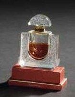 LALIQUE Parfums - Fondé par Marie-Claude LALIQUE (1935-2003)
Chèvrefeuille, modèle créé en 1992 Flacon de parfum d'après un dessin de Marie-Claude Lalique. Corps en cristal soufflé moulé et en partie satiné. Bouchon en cristal moulé pressé et, en partie, satiné. Jus résiduel. Fêlure. Édition limitée et numérotée E 0914. Signé LALIQUE © France en lettres cursives vers la base. Hauteur: 8,5 cm Provenance: Collection de la Côte d'Azur