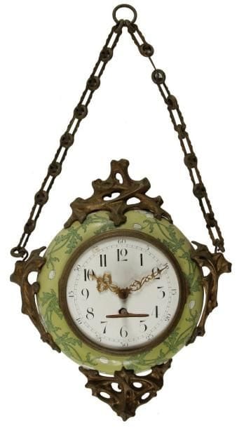 Travail ART NOUVEAU d?après Hector GUIMARD (1867-1942)
Pendule murale, dite Boulangère. Le boîtier émaillé polychrome, au décor floral, est orné de motifs coup de fouet en pourtour réalisés en bronze doré. Cadran émaillé, indexé en chiffres arabes. Suspentes et système d?accroche d?origine. Circa 1900. Dorure altérée et petits éclats d?émail sur le cadran. Hauteur totale: 53 cm. Historique:. Selon plusieurs documents écrits, des versions approchantes de cette pendule, réalisées en très grand format, auraient figuré dans le Metro parisien au début du XXe siècle