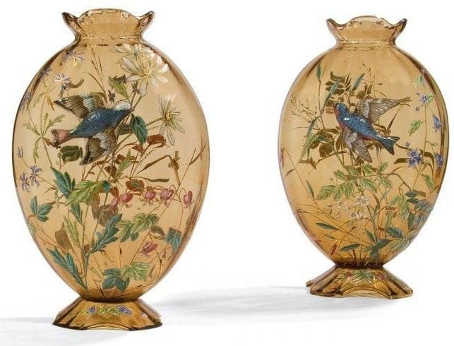 Travail des ANNÉES 1890/1900
Rare paire, formant pendants, d?importants vases ovoïdes, méplats et côtelés, reposant sur une base en découpe et à col festonné. Épreuves en verre fumé au riche décor double face de fleurs champêtres réalisé aux émaux polychromes. Un oiseau en verre modelé à chaud et émaillé est appliqué sur chacun des vases. Nombreux rehauts de dorure dans les décors, les bases et les cols. Un éclat, dans l?épaisseur, à l?intérieur de l?une des bases. Hauteur: 36,5 cm