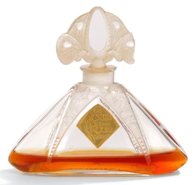 SALANCY Parfumeur & Julien VIARD Concepteur
Le Roman d?une rose, modèle créé vers 1920. Flacon de parfum. Corps en verre soufflé moulé et, en partie, satiné. Bouchon en verre moulé pressé et, en partie, satiné. Présenté dans son écrin triangulaire gainé de cuir teinté vert (intérieur assorti en satin). Bouchon fixe et présentant une infime fêlure dans le décor en relief. Complet de son étiquette dorée Le roman de la Rose - SALANCY, le titrage et le marque sont repris en lettres cursives à l?or sur le coffret. Marqué SALANCY et monogrammé J.V. (Julien VIARD) en relief sous la base du flacon. Hauteur: 9 cm. Coffret: 4 x 10 x 10 cm