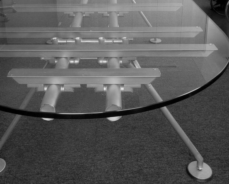 Norman FOSTER (né en 1935)
Nomos, série créée en 1986. Grande table bureau à dessus oblong. Structure squelette, formant piétement, réalisée en métal et complétée par des cornières soutenant le plateau et par des patins de réception circulaires. Édition ancienne par TECNO Milan. Plateau constitué d?une épaisse dalle de verre achevée en joint poli. 73 x 270 x 118 cm