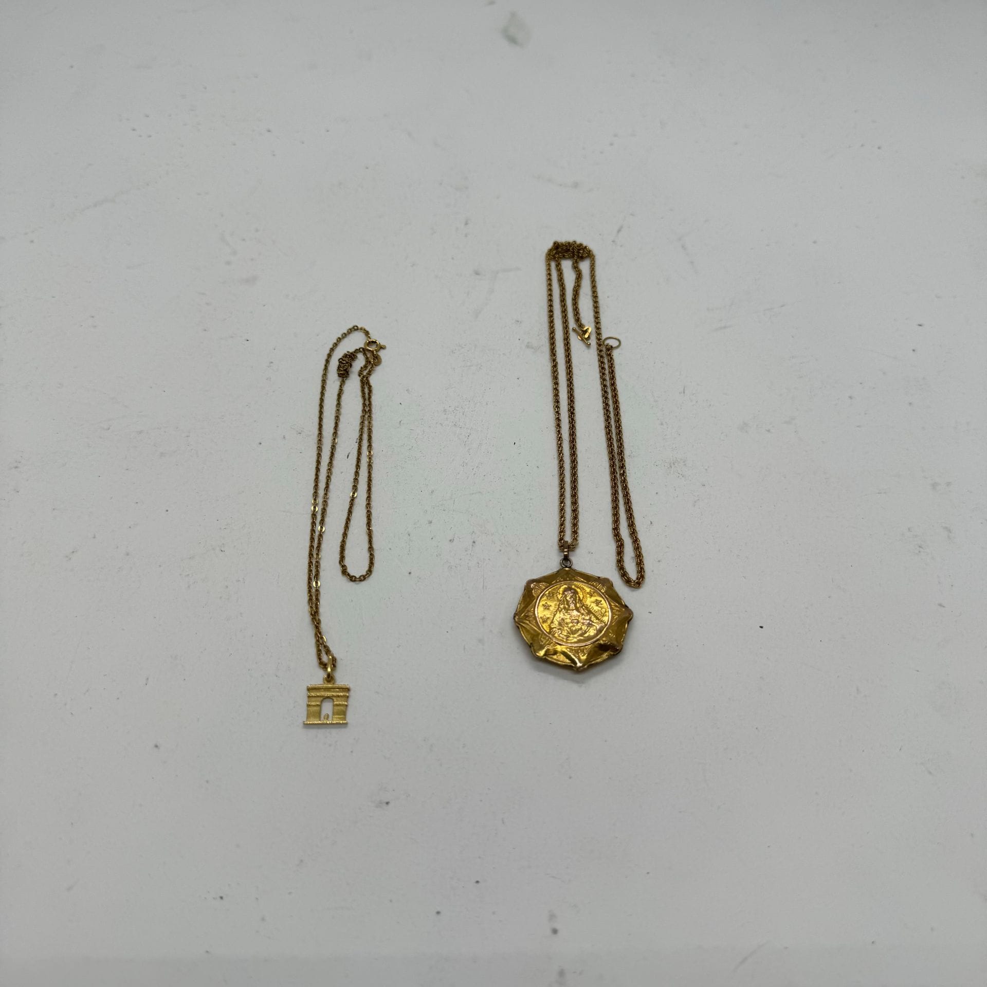 Lot comprenant : 
Une chaine en or 750/°°° et pendentif en forme d'Arc de triomphe en en or 750/°°°, poids net: 4.26 g.
Une chaine en or 585/°°° et un pendentif en or 375/°°°, poids brut : 13.44g.