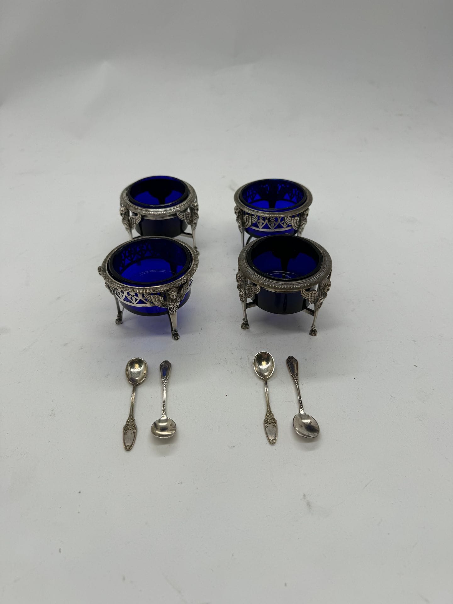 FRANCE 1798 - 1809 
Lot de 4 salières de table à décor de sphinge en argent 925/°°°
4 cuillerons en métal argenté
intérieur de verre bleu. 
Poids net : 332 g