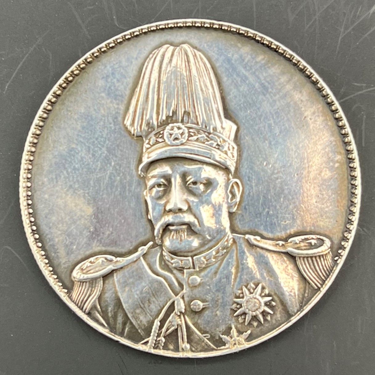 CHINE (République). 
Yuan Shih-kai, fondateur de la République.
-Dollar ou Yuan en argent (26,82g) frappé en 1914 (ou refrappe après 1918), 
-son buste de face en uniforme portant casquette à aigrette. A été nettoyé.
KM.322 ou 322.1
-TTB