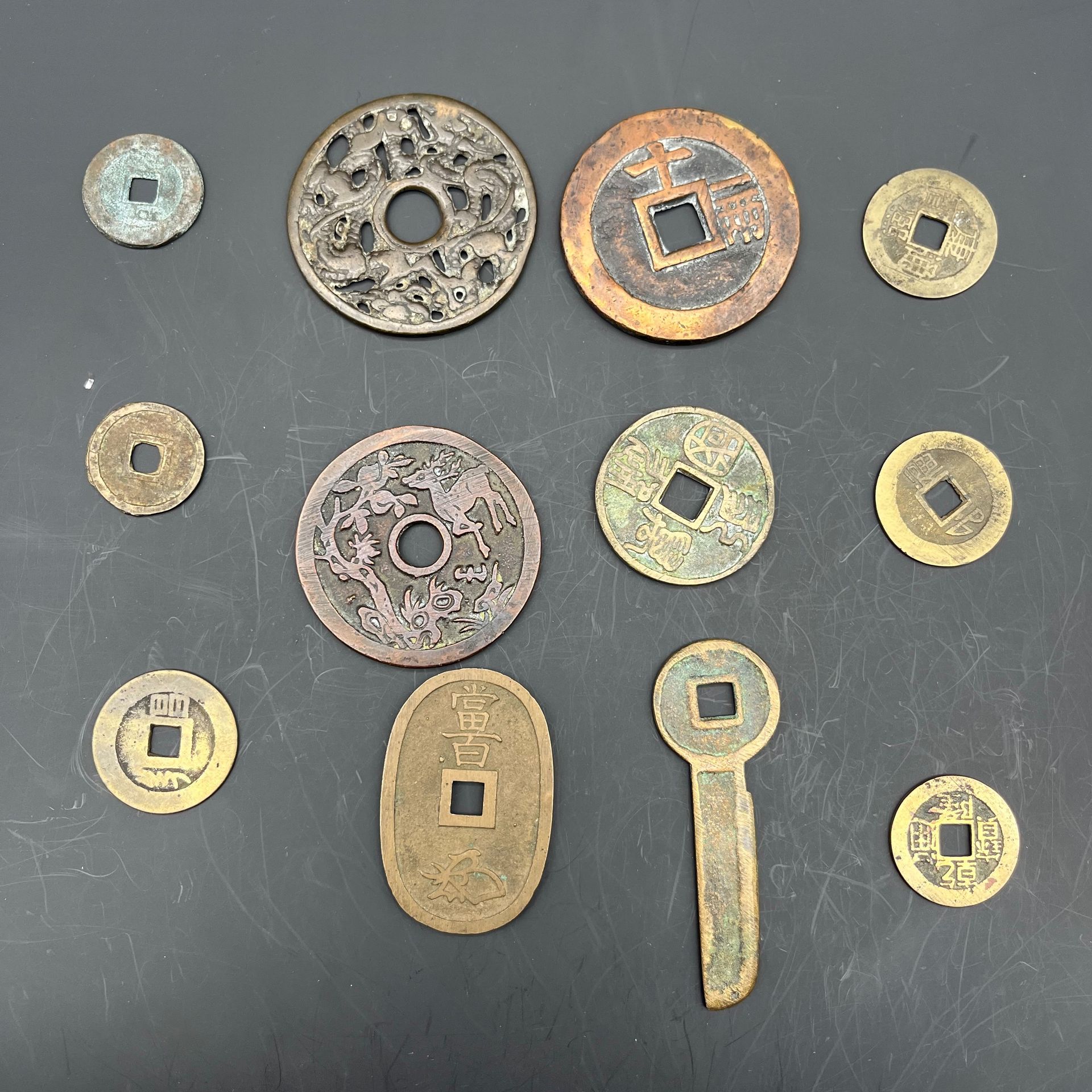 Lot de 12 sapèques chinoises, indochinoises et japonaises, talismans et amulettes, monnaie clé. 
En bronze. 
Etat variés, 
sans garantie