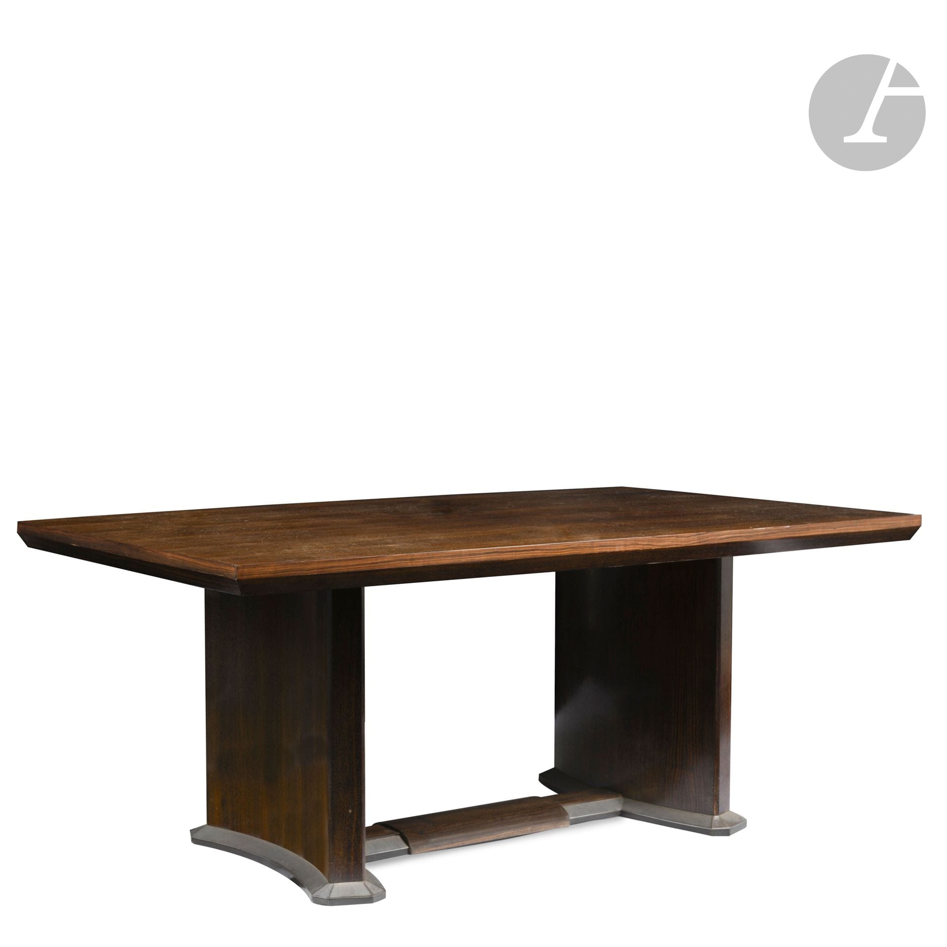MAISON DOMINIQUE – ANDRÉ DOMIN (1883-1962) & MARCEL GENEVRIÈRE (1885-1967)
Intéressante table, pouvant former bureau plat, en placage d’ébène de Macassar. Le plateau présente un large chanfrein sur le dessous de son pourtour et des parties longitudinales légèrement bombées. Les deux pieds cintrés reposent chacun sur une base à pans coupés, parée de métal nickelé, et sont réunis par une entretoise également parée de métal et accueillant une partie bombée centrale formant repose pieds. Années 1930. H.72cm – L.179cm – l.114cm

Bibliographie:
- L’Art vivant – N° 161 de juin 1932. Modèle identique reproduit page 299.
- Art et Industrie – N° 8 d’août 1932. Le dessin du modèle de notre table reproduit page 34.
- Mobilier et Décoration – N° 6 de juin 1932. Modèle identique reproduit page 299.
- L’Architecture d’aujourd’hui – N° 4 de mai 1932. Modèle identique reproduit page 79.
- Art et Décoration - Juillet 1932. Modèle identique reproduit page 220.
- Félix Marcilhac – André Domin & Marcel Genevrière, décorateur–ensemblier du XXe siècle- Les Éditions de l’Amateur, Paris, 2008. Modèle identique reproduit page 103.
