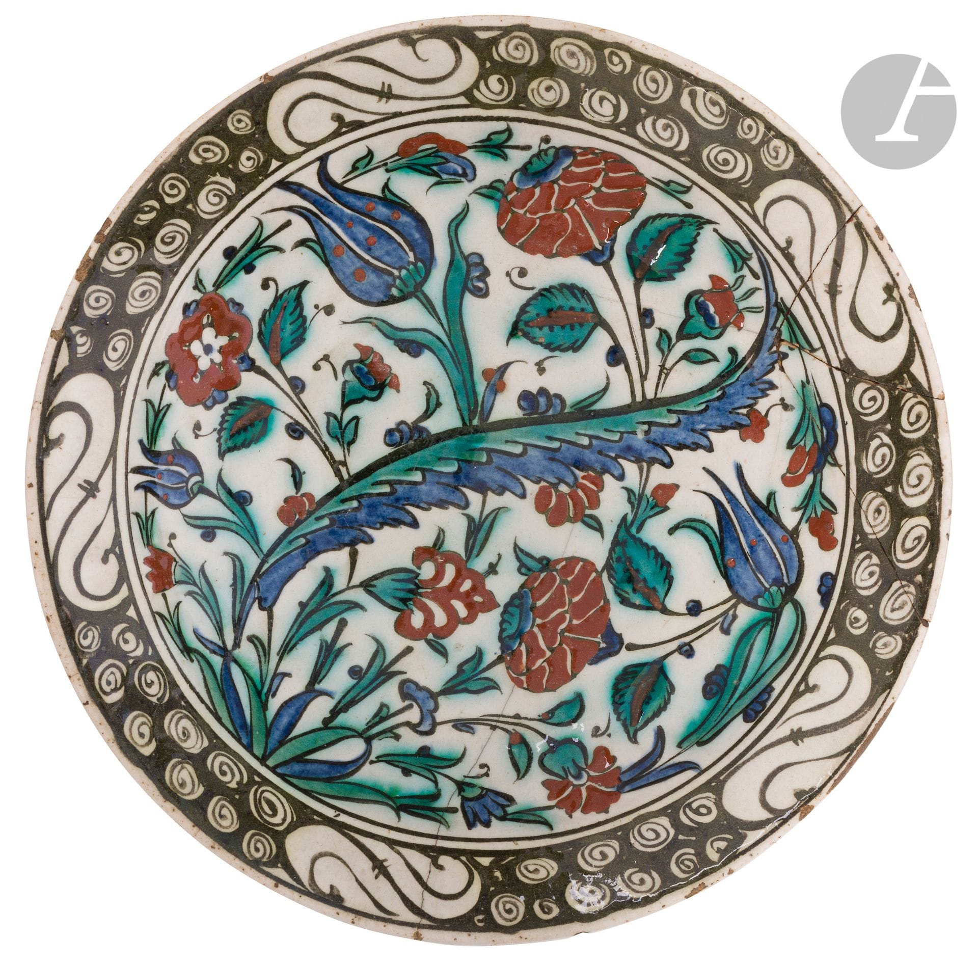 Tabak dish with floral decoration, Ottoman Turkey, Iznik, early 17th century
Circular siliceous ceramic dish with polychrome painted decoration on white slip, under a transparent glaze, of a floral composition combining tulips, roses, budding flowers and blossoming carnations around a saz leaf. A frieze of waves and stylized black rocks runs along the rim. 
Diameter: 29.2 cm
Cracks, hanging hole, reattached breaks, minor chips and chips.