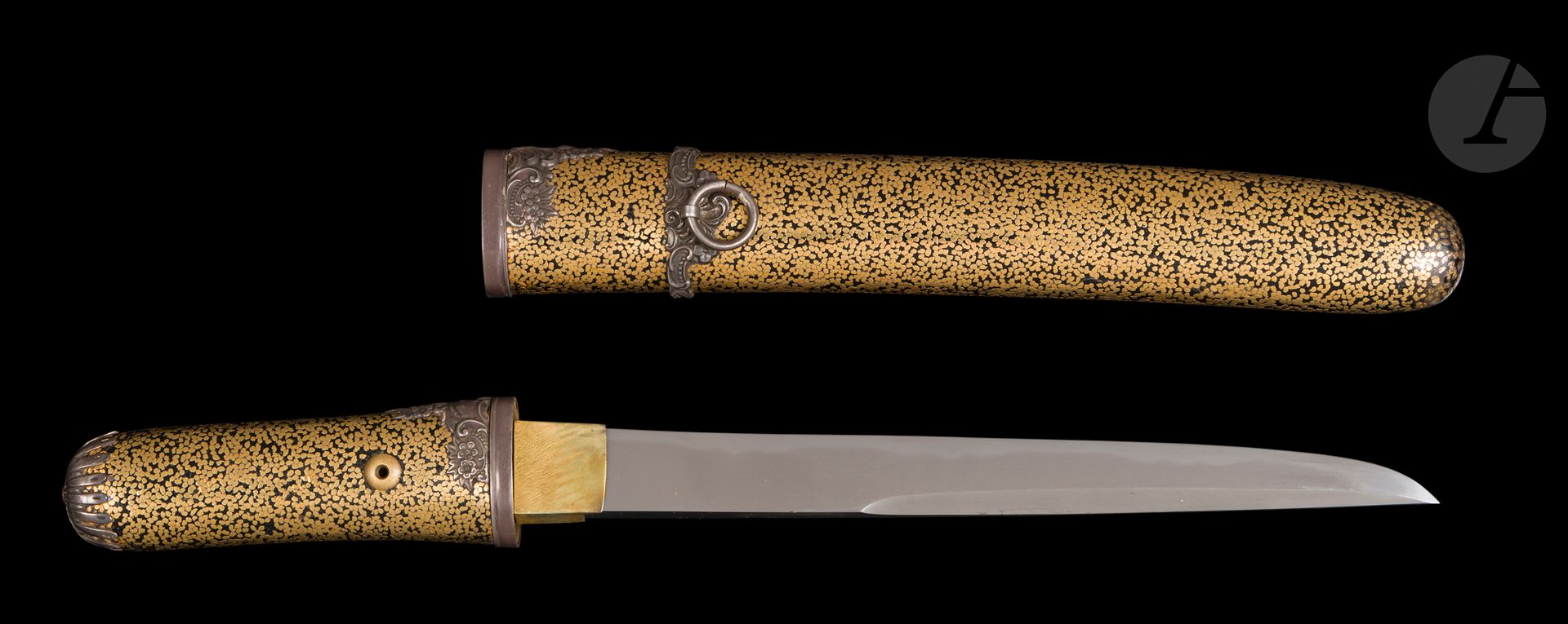 Kwaï ken, Japon, époque Meiji (1868-1912)
Lame koto, unokubi zukuri, iori mune, mu zori, mokume hada, gunome hamon. Étant donné la largeur importante du munemachi, il s’agit certainement d’une lame de yoroi doshi (perce-armure), montée en kwai ken. Koshirae en bois laqué noir et incrusté de cuivre doré. Fuchi, koiguchi et semegane en laque d’argent à motifs de rinceaux fleuris. Montures de l’époque Meiji, de style rococo. Kurigata en forme d’anneau. Kashira en forme de chrysanthème. Mekugi à vis. Boîte en bois à décor de mon laqués rouge de type maru ni age-ha no cho – « Papillon aux ailes levées dans un anneau », mon principal du clan Ikeda de Tottori. Pochette en soie blanche.
Nagasa : 18,8 cm
Petite restauration au bout du fourreau.