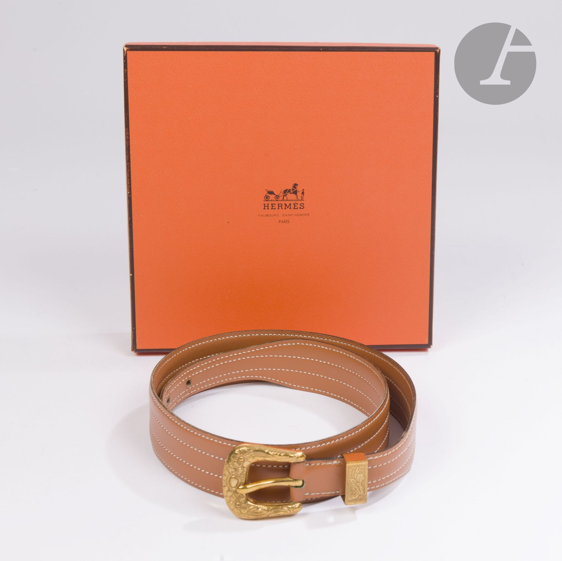 HERMES Paris Made in France 
Ceinture en cuir caramel surpiqué crème, boucle et garniture en métal doré à décor de fleurs. Année 1973. Taille 75-80 environ. L : 89 cm. Dans sa boîte avec petite housse à boucle