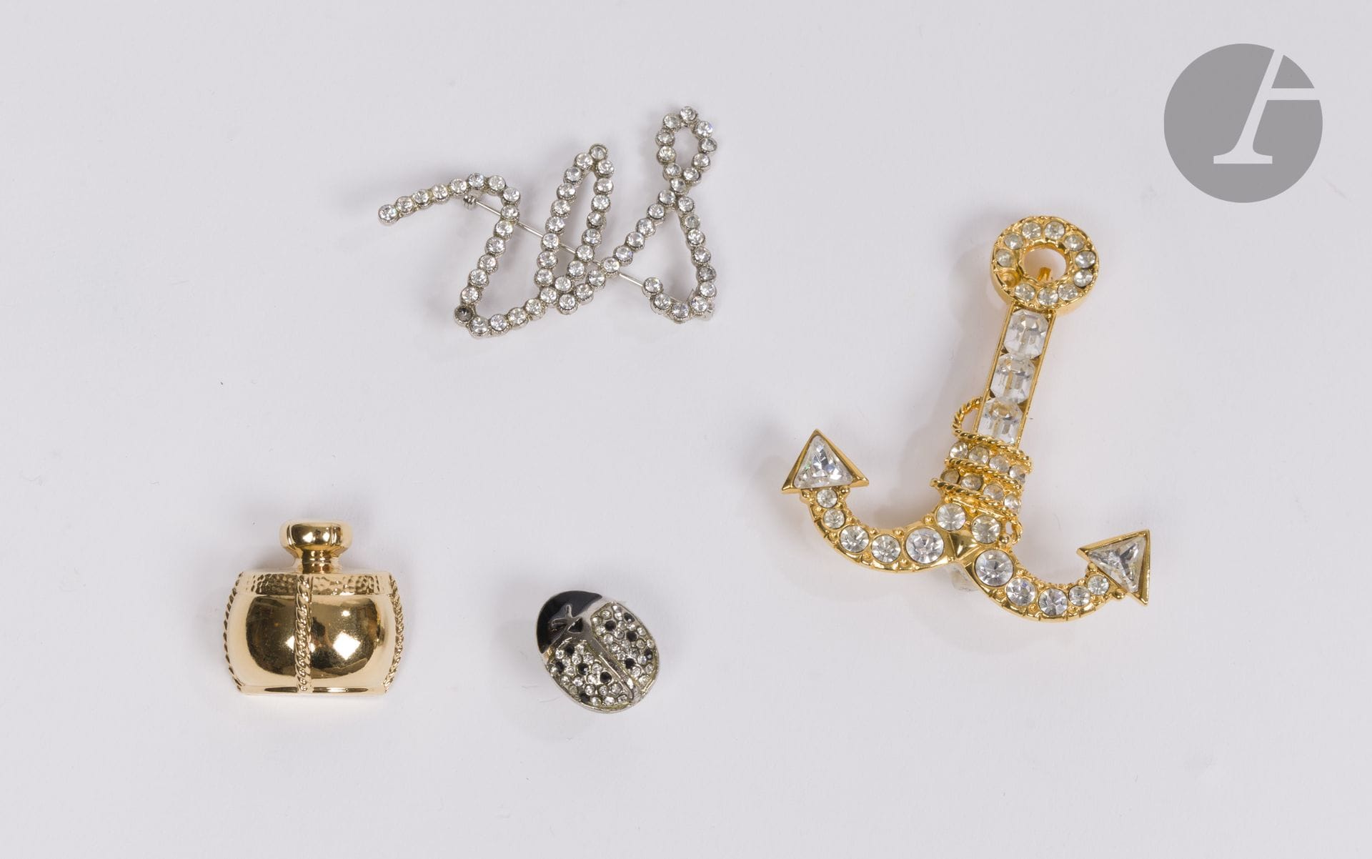 Lot de 4 bijoux fantaisie comprenant une broche ancre signée SCHERRER, une broche SR à strass non signée mais portant une étiquette Sonia Rykiel, un pins coccinelle signé Sonia RYKIEL et une broche parfum YSL