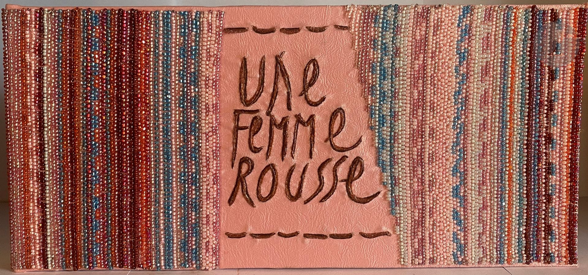 CORTOT (Jean).
Une femme rousse.
[Paris : Jean Cortot], 1995. — In-4 oblong, soie rose comportant le titre brodé sur le premier plat et le nom de l'artiste ainsi que l'année également brodés sur le second, décor de filets de perles multicolores collés verticalement sur les plats et le dos, dos lisse, emboîtage peint d'édition.

Livre d'artiste tiré à seulement 4 exemplaires, dont le texte a été entièrement brodé sur 8 morceaux de soie peinte, doublés de soie blanche. Ces huit pièces sont reliées, une neuvième a été ajoutée, volante.

Exemplaire numéro II, parfaitement conservé.