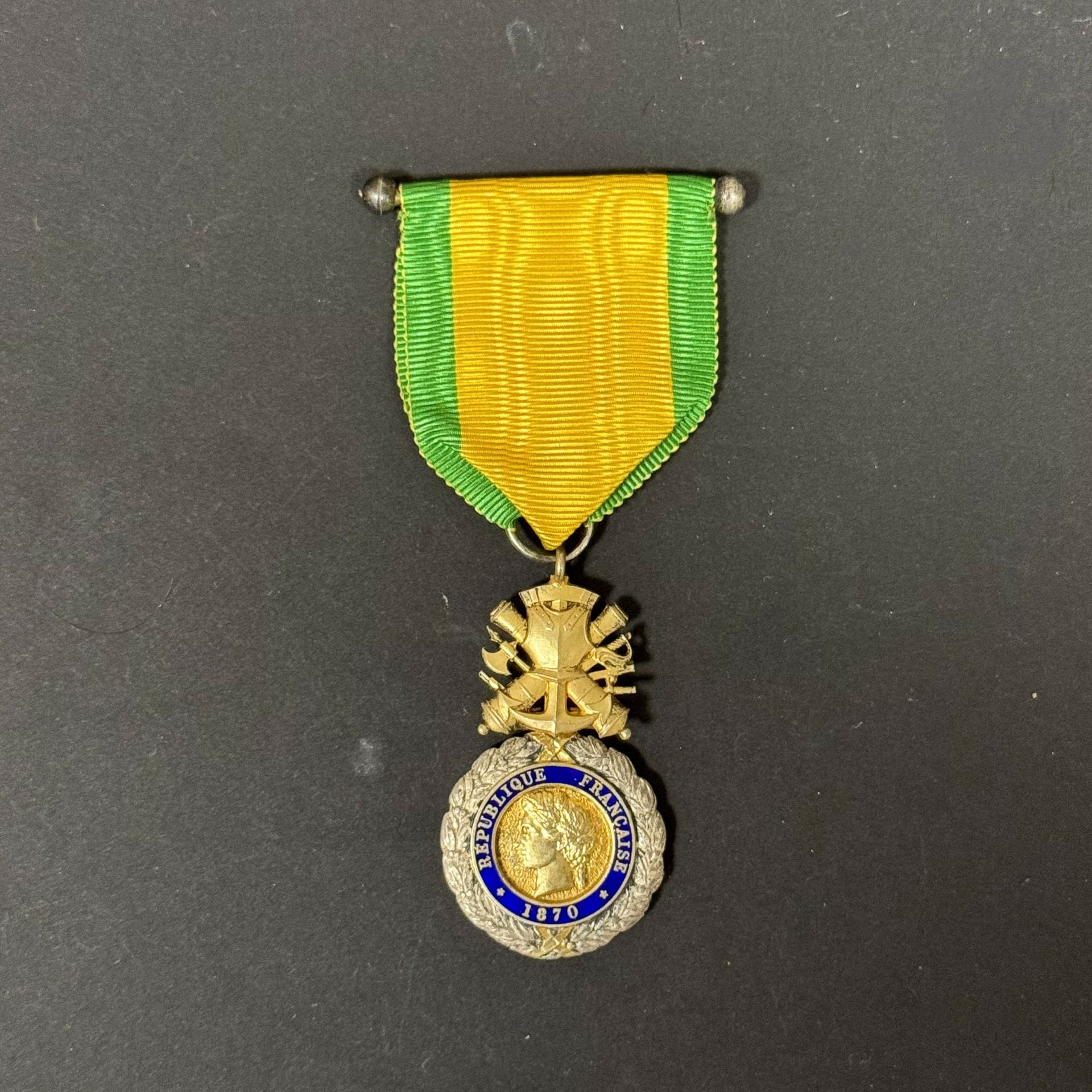 FRANCE 
MÉDAILLE MILITAIRE
Médaille militaire IIIe République, fabrication dite « de Londres » 
En argent, vermeil et émail. Non poinçonnée. 
Ruban cousu avec barrette de présentation. 
T.T.B. 

Historique : 
Cette fabrication constitue une rare fabrication de Londres d’époque 2e guerre mondiale. En effet celle-ci est non poinçonnée et possède des caractéristiques que l’on ne retrouve pas sur les fabrications françaises (la présence de trois cylindres de taille identique à la charnière, mâchoire anguleuse du profil du centre, l’absence de poinçon et le ruban soyeux).
