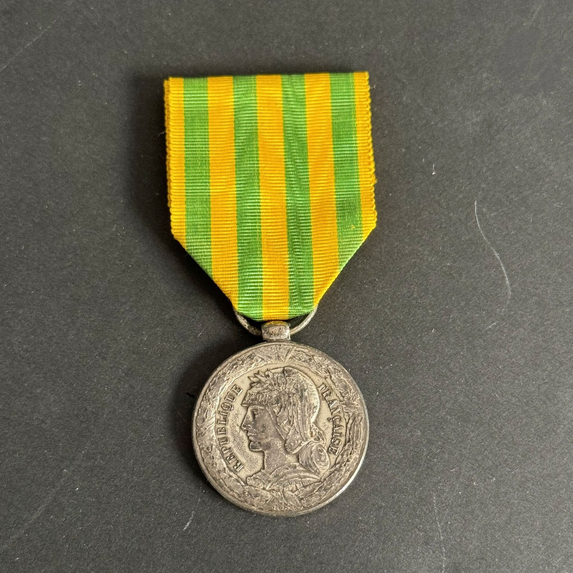 FRANCE 
MÉDAILLE DU TONKIN (1885)
Médaille du Tonkin, modèle de la Marine. 
En argent, à bélière olive. Poinçon corne d’abondance. Ruban. 
27 mm - Poids net 14 g
T.T.B.