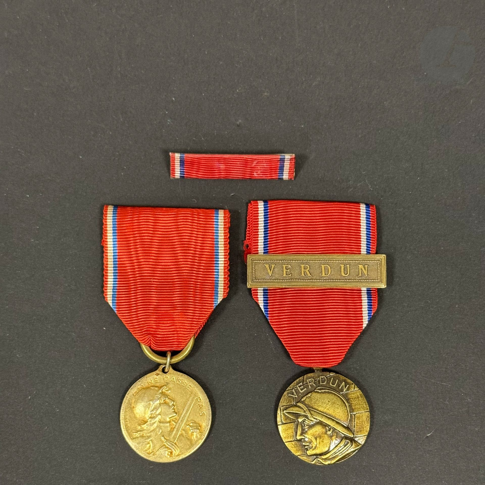 FRANCE 
MÉDAILLE DE VERDUN 
Deux médailles : 
- une du modèle dit anonyme de fabrication tardive, en bronze. Ruban à agrafe Verdun. Avec un rappel de décoration. 
- une de fabrication Vernier, en vermeil. Poinçon tête de sanglier et d’orfèvre. Rubans. 
T.T.B. à SUP.