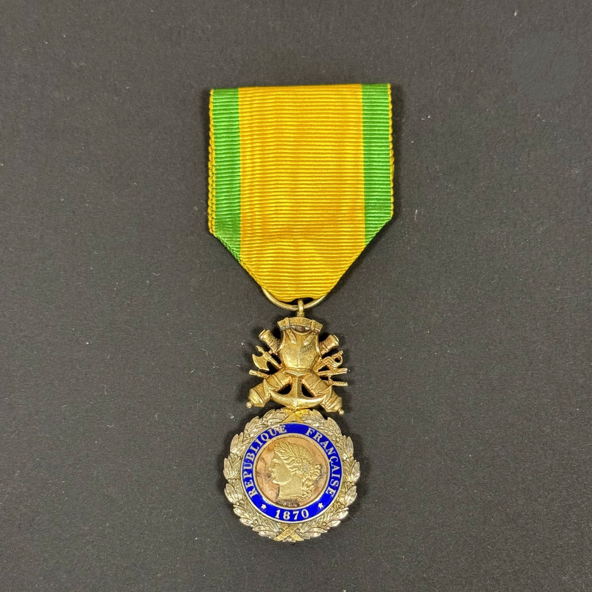 FRANCE 
MILITARY MEDAL 
Goldsmith's pattern military medal with biface trophy with barrels 
In vermeil. Boar's head hallmark. Enameled vermeil center (small chips) in three parts. Ribbon. 
49 x 26 mm - Gross weight: 17.8 g
T.B. to T.T.B. Third Republic.