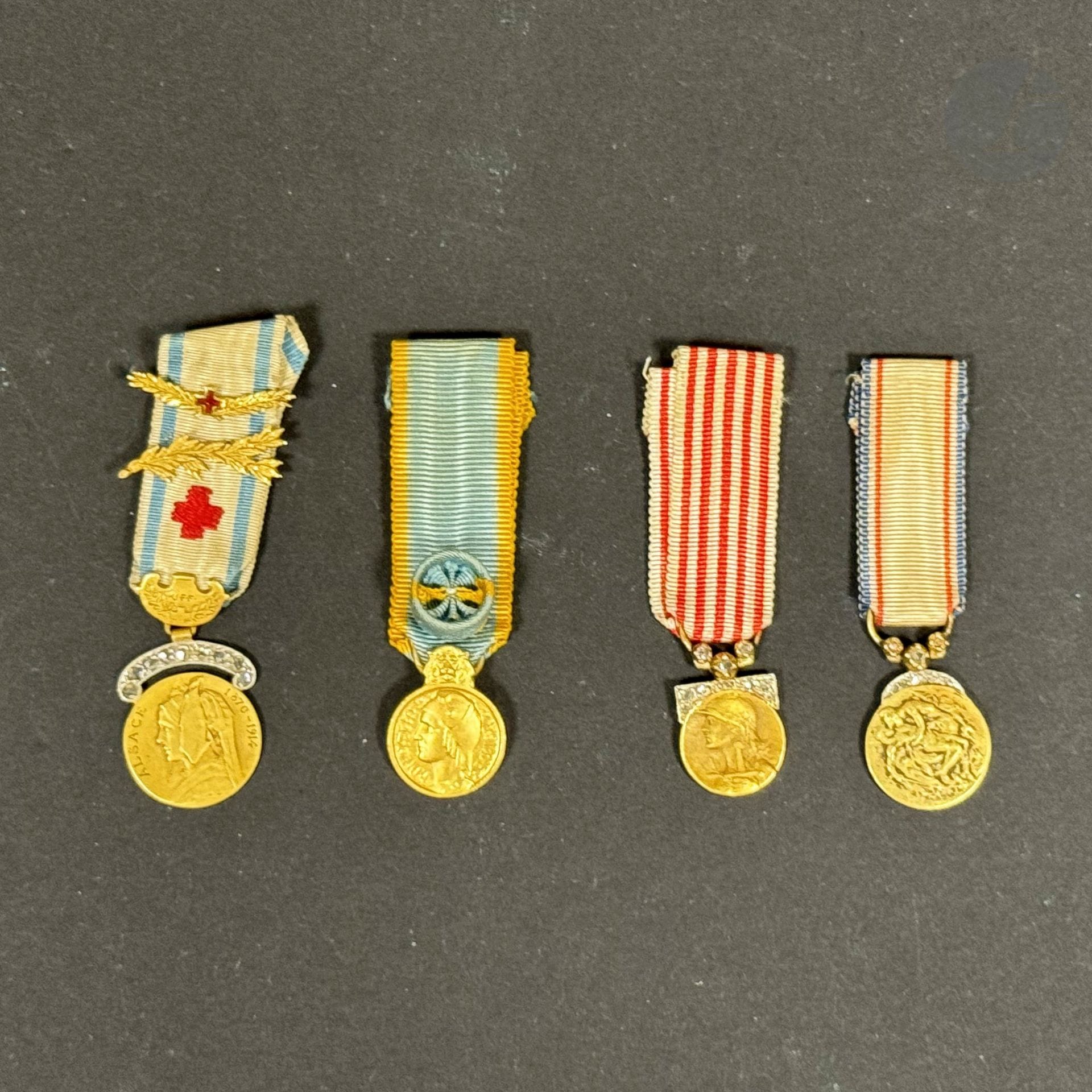 FRANCE 
Réunion de quatre miniatures en or, dont trois modèles de luxe : 
- médaille de l’Union des femmes françaises. En or ciselé. Traces de poinçon sur l’anneau. Garni sur la bélière de petits brillants. Ruban à deux palmes en or ciselé ; 
- médaille de la Reconnaissance française. En or. Garnie sur la bélière de brillants. 
- médaille commémorative de la guerre 1914-1918. En or. Garnie sur la bélière de brillants. 
- Médaille d’or de l’éducation physique. En or. Poinçon de la Monnaie de Pairs. 
Rubans. 
Poids brut : 10,5 g