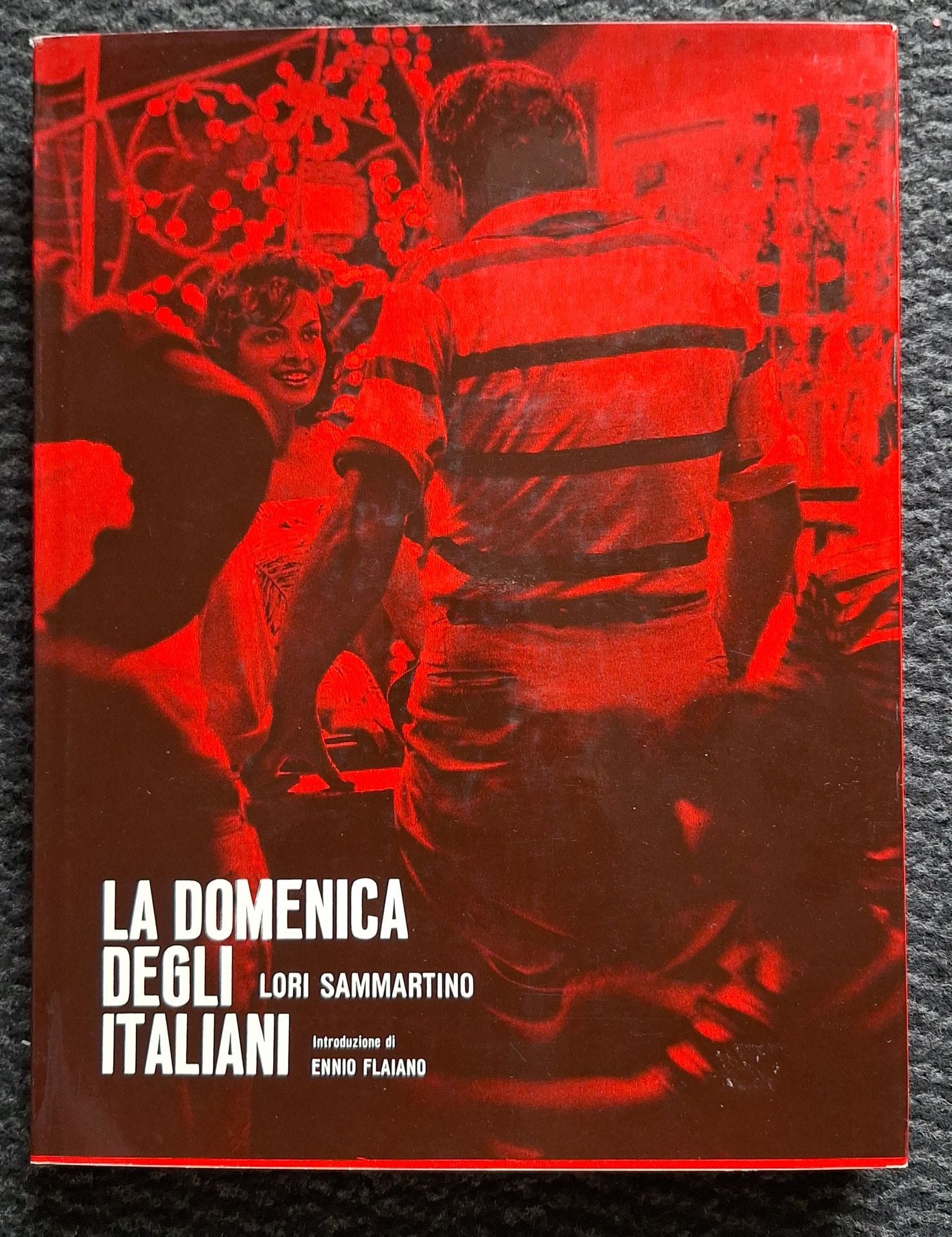 SAMMARTINO, LORI (1934-1971)
La domenica degli italiani.
Minerva, Milano, 1961.
In-4 (28,5 x 22 cm). Édition originale. Texte d’Ennio Flaiano. 120 photographies reproduites en héliogravure. Relié noire avec titre en rouge sous jaquette illustrée. Très bel exemplaire, avec jaquette parfaite.